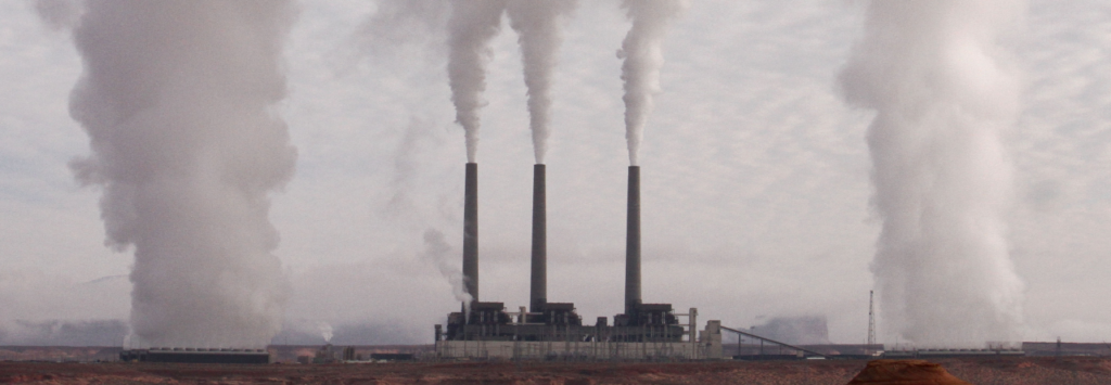 trois cheminée d'usine crachent leur fumée