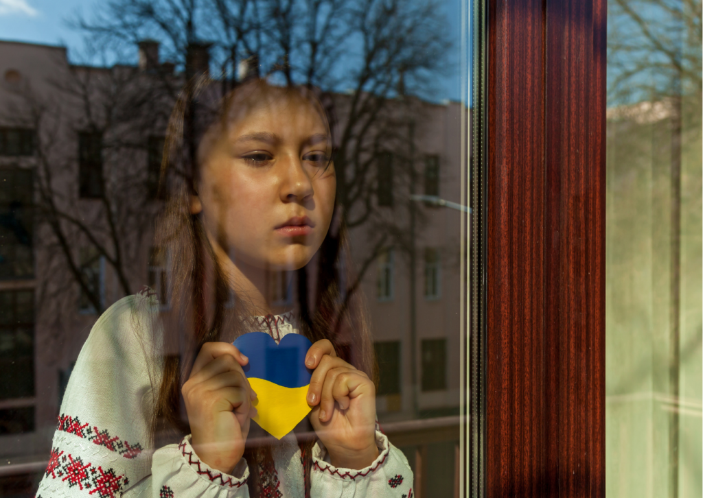 Enfant ukrainien derrière une vitre avec cœur aux couleur du drapeau