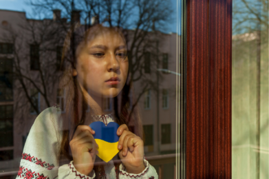 Enfant ukrainien derrière une vitre avec cœur aux couleur du drapeau